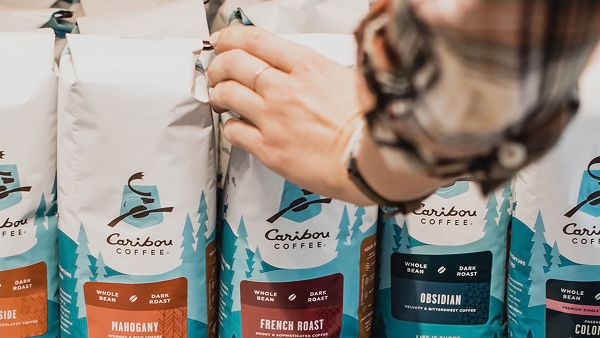 A customer picks out a bag of Caribou Coffee French Roast