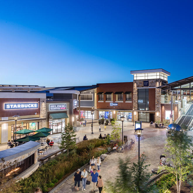 An overhead shot of an outdoor Simon mall with a Starbucks in the foreground and luscious green trees and bushes decorating the pathways.
